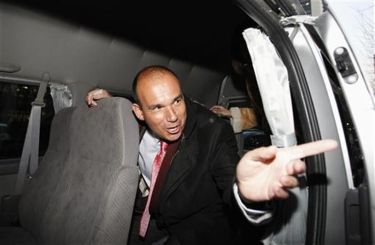 Former Olympus CEO Michael Woodford speaks to a reporter from inside a van as he leaves a news conference in Tokyo