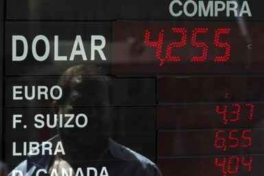 A man is reflected an electronic board showing currency exchange rates at a money exchange in Buenos Aires