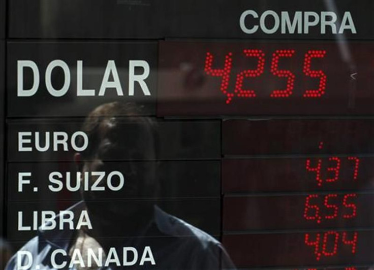 A man is reflected an electronic board showing currency exchange rates at a money exchange in Buenos Aires