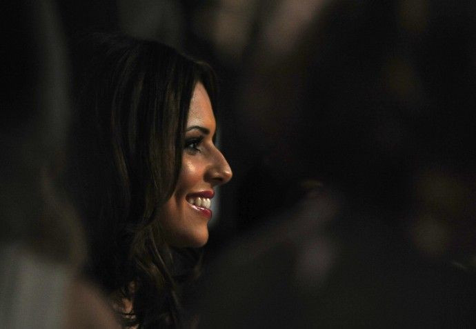 Girls Aloud singer Cole smiles as she watches performers during the Brit Awards at Earls Court in London