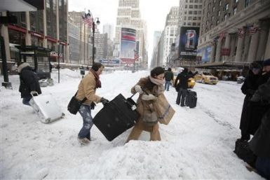 Travellers carry their luggage through a snow bank on 7th Avenue in front of Penn Station after a snow storm in New York December 27, 2010.