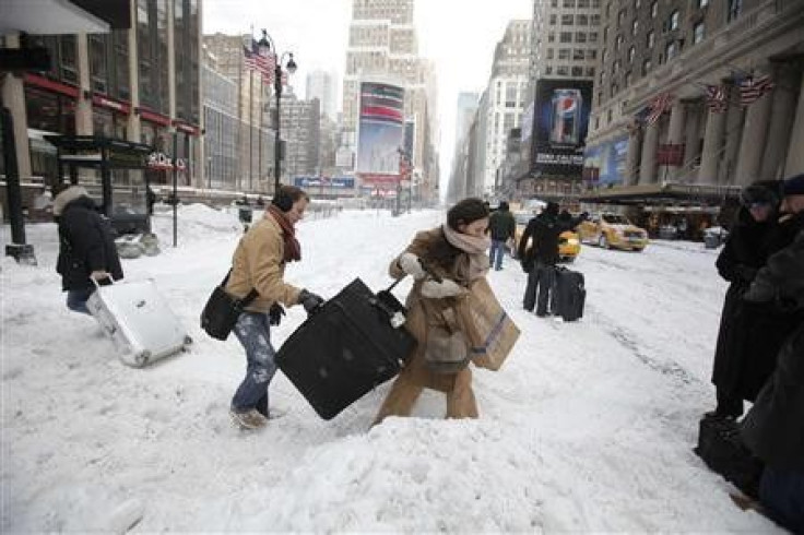 Travellers carry their luggage through a snow bank on 7th Avenue in front of Penn Station after a snow storm in New York December 27, 2010.