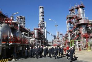 Spain's King Juan Carlos walks with members of Cepsa during his visit to a Cepsa refinery in Palos de la Frontera