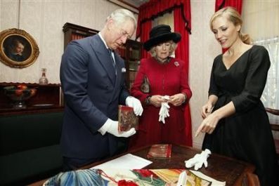 Britain&#039;s Prince Charles and his wife Camilla, Duchess of Cornwall, look at two first editions of a Charles Dickens book, as they stand with actress Gillian Anderson during a tour of the Dickens Museum in London