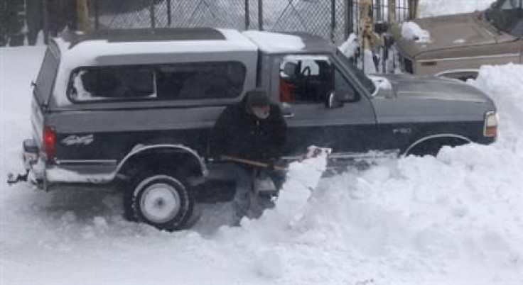 A truck stuck in a snow bank is shoveled out as blizzard-like conditions due to high winds continue in Hoboken
