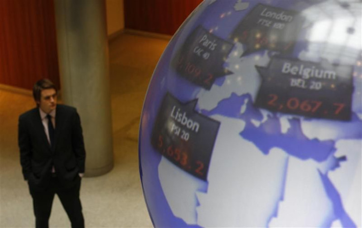 A man stands next to a globe displaying international stock market prices at the London Stock Exchange in the City of London