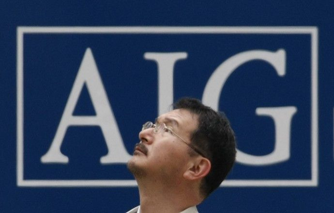 A man stands in front of an AIG logo in Tokyo