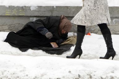 Woman begs for money as people pass by, with the air temperature at about minus 13 degrees Celsius, in Kiev