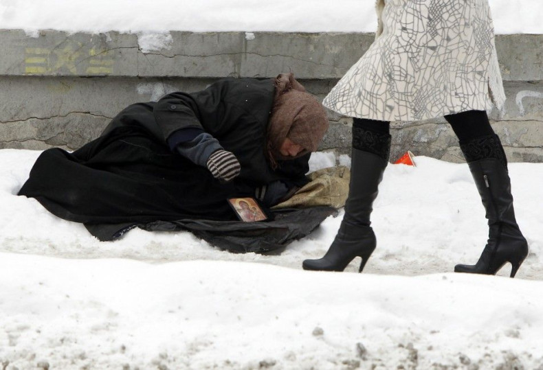 Woman begs for money as people pass by, with the air temperature at about minus 13 degrees Celsius, in Kiev