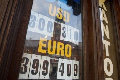 The currency exchange rates are displayed at an exchange office with the Royal Castle reflected in the window in Warsaw
