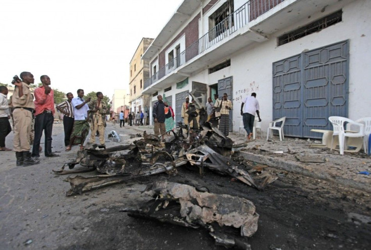 Somali people stand near the scene of a suicide car bomb that exploded leaving scores dead near Muna Hotel in Mogadishu