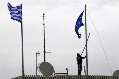 A man tries to replace a torn-off EU flag atop the Greek Ministry of Foreign Affairs in Athens