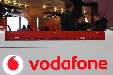 The Vodafone logo is seen at the counter of the shop as customers look at mobile phones in Prague