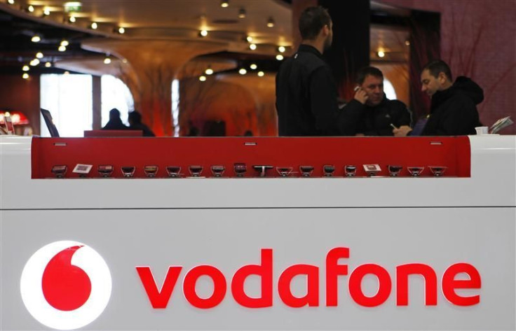 The Vodafone logo is seen at the counter of the shop as customers look at mobile phones in Prague