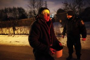 A homeless man holds a pot of a soup distributed by municipal officers at an allotment garden in Warsaw