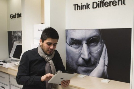 Man checks Apple iPad as he stands next to portrait of late Apple co-founder Jobs at shop in Payetakht computer centre in northern Tehran