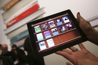A woman holds up an iPad with the iTunes U app after a news conference introducing a digital textbook service in New York