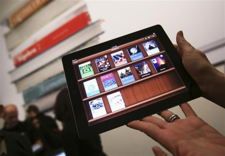 A woman holds up an iPad with the iTunes U app after a news conference introducing a digital textbook service in New York