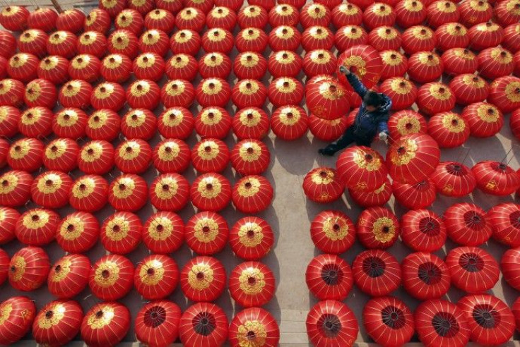 A worker lays out newly made red lanterns to dry at a lantern factory in Jishan county, Shanxi province
