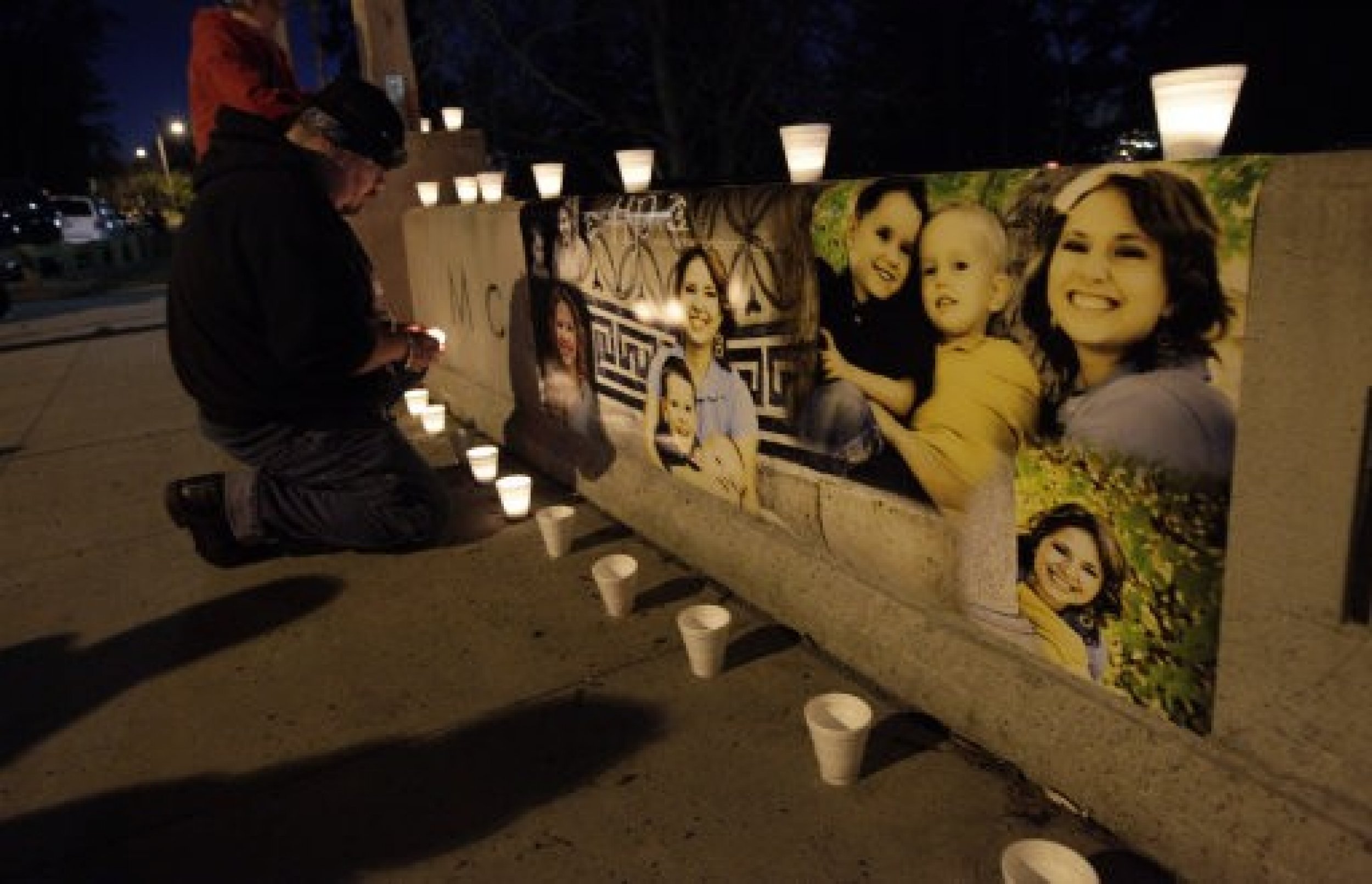 Ken Landgrebe lights a candle next to photographs of Susan Cox Powell and her sons Braden and Charlie,