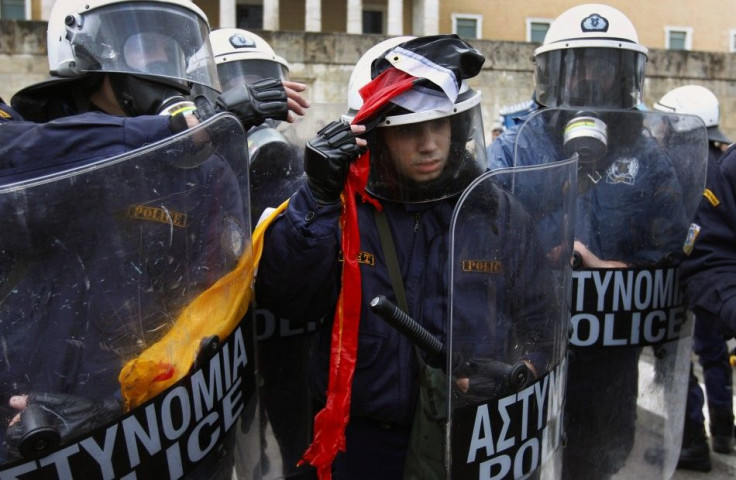 A riot policeman removes a torn German flag thrown by anti-austerity protesters during scuffles in front of the parliament in Athens