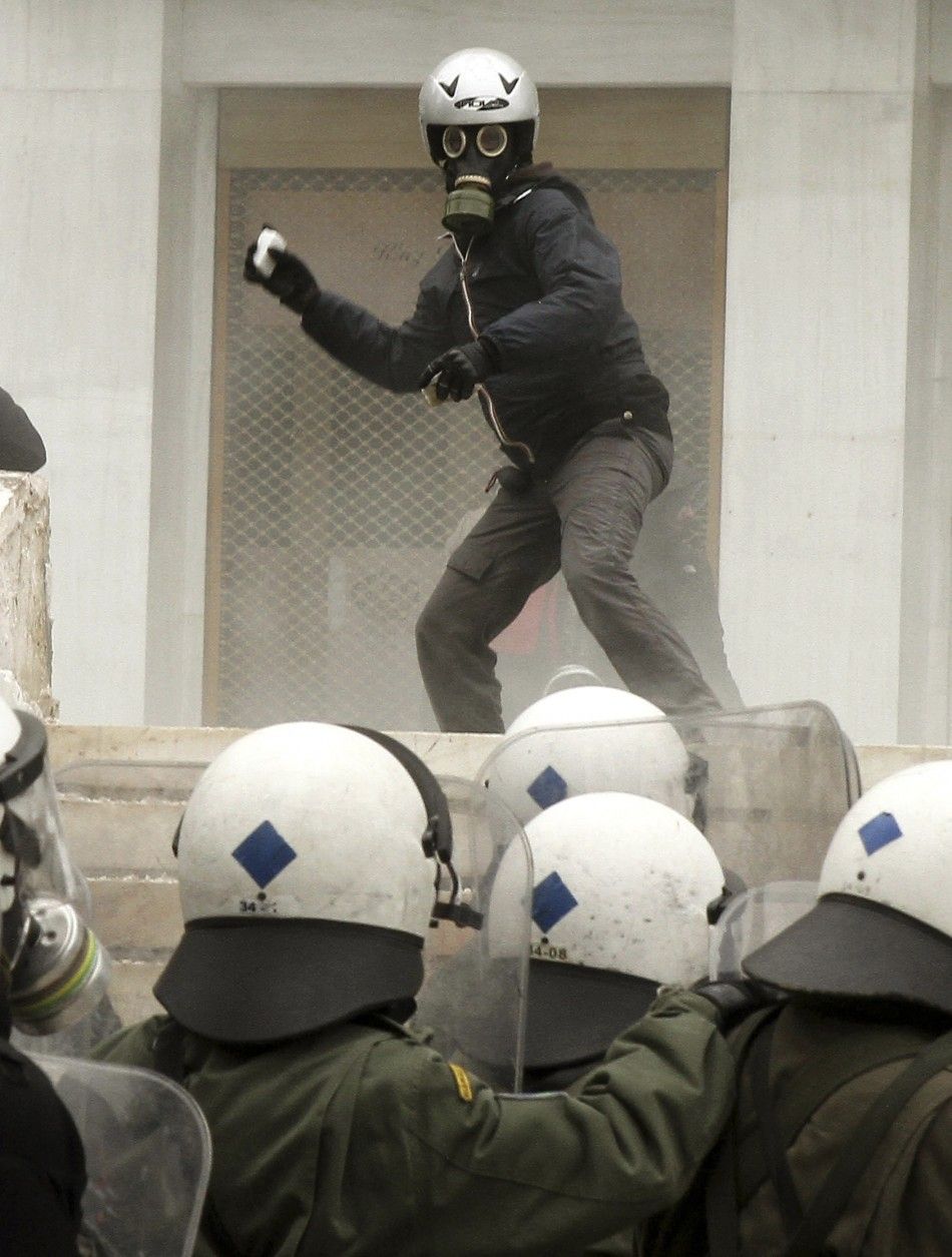 A protester hurls rocks at riot police in Athens Friday