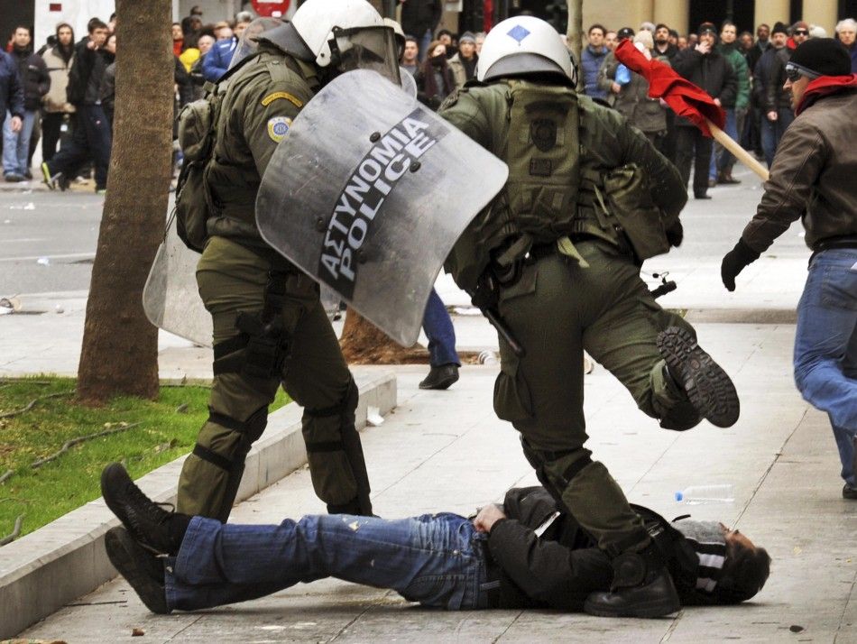 A riot police officer kicks a downed protester during demonstrations in Athens Friday