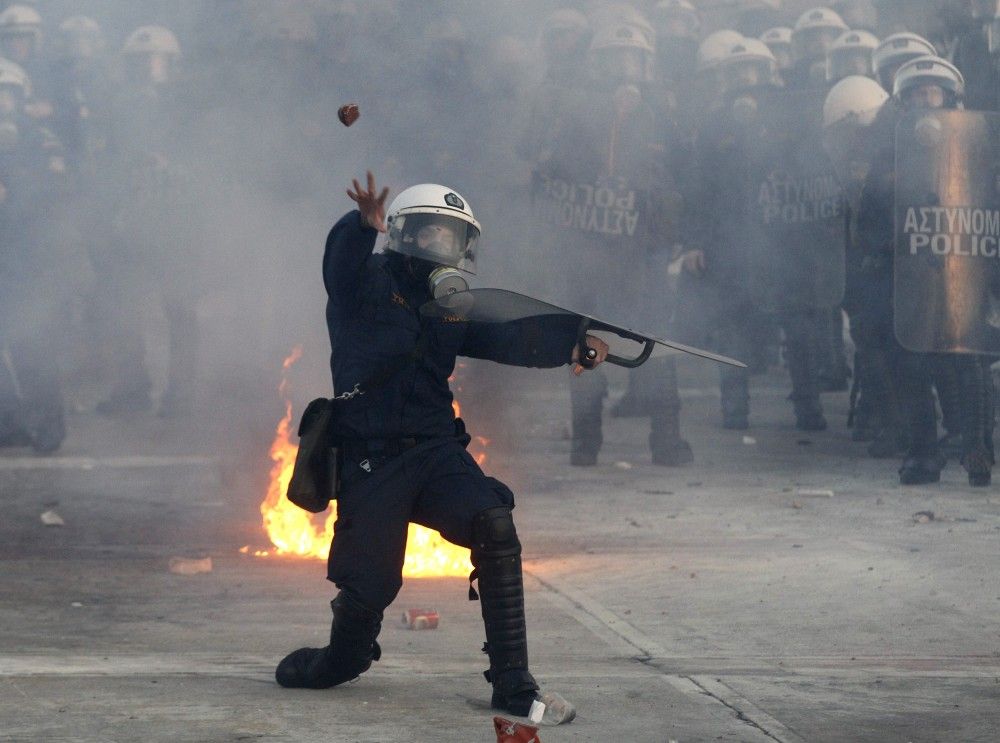 Greece Blurring the line between demonstrators and peace officers, a Greek policeman throws a rock at protesters Sunday.