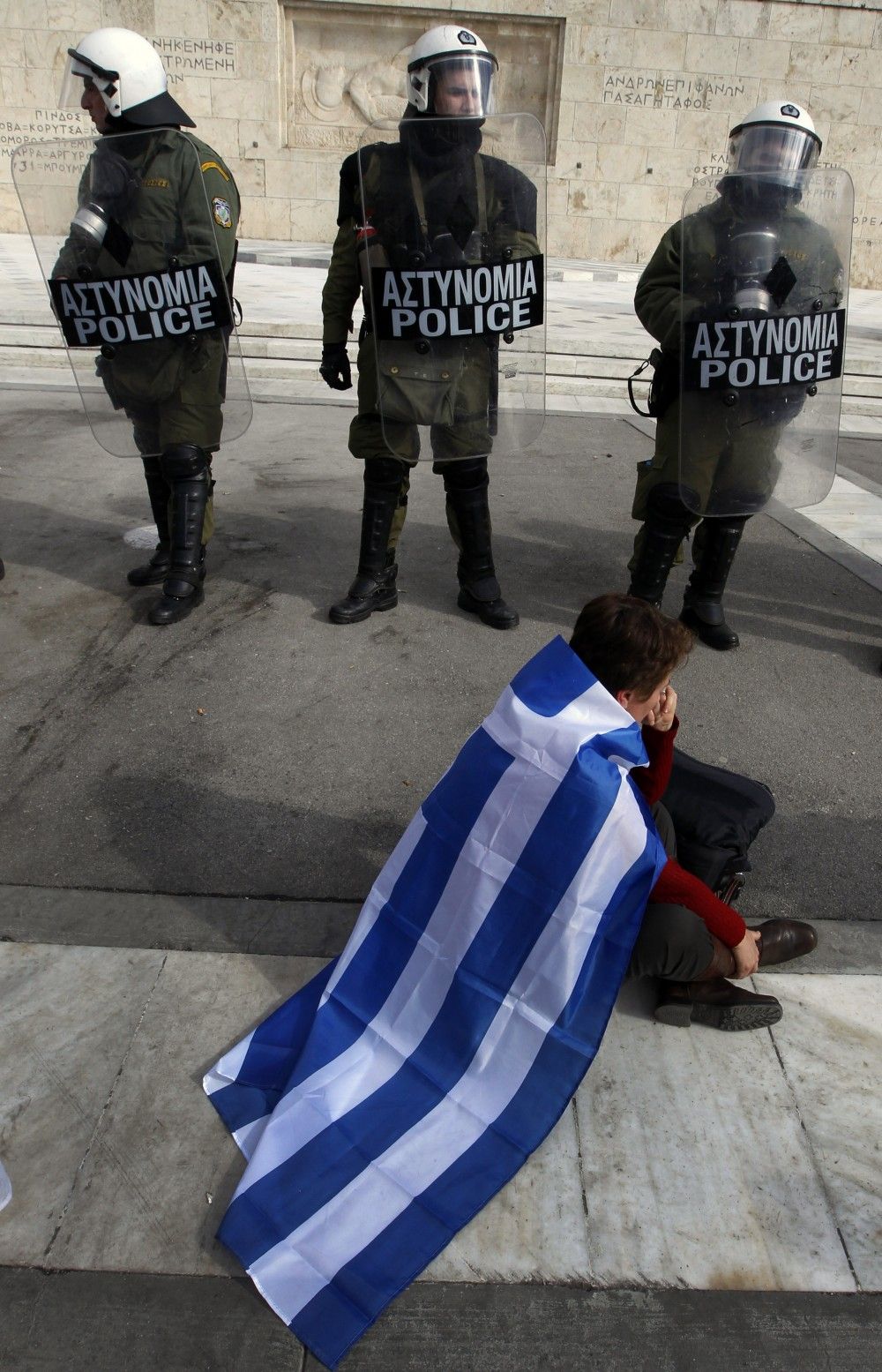 Greece A demonstrator sits in front of officers guarding the countrys parliament in Athens Saturday.
