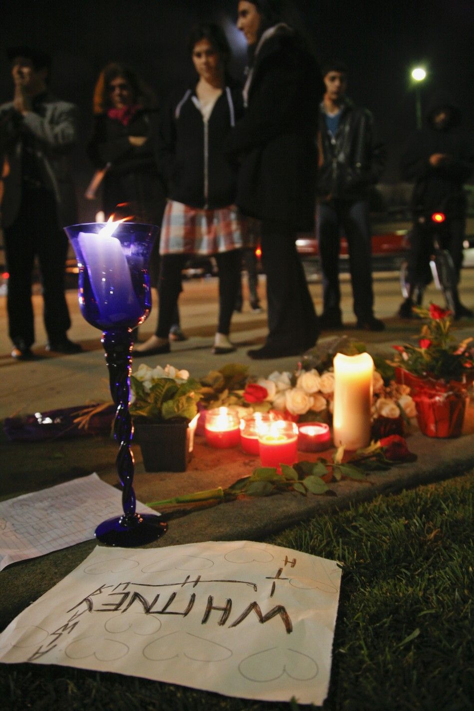 Mourners gather at a makeshift memorial on the corner of Santa Monica and Wilshire Boulevards as they mourn the death of singer Whitney Houston in Beverly Hills, California