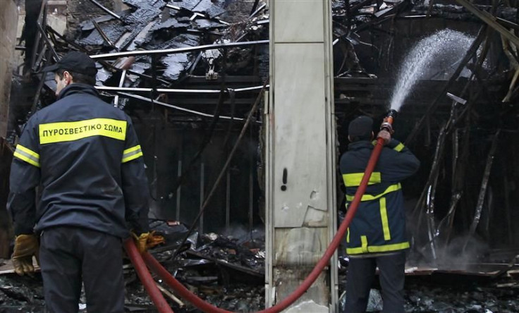 Firemen hose down a burned-out shop after a night of violence following the Greek parliament approval of a deeply unpopular austerity bill in Athens