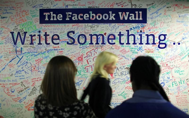 People walk past the Facebook wall inside their office in New York